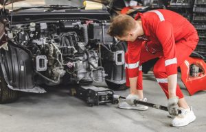 Mechanic lifts automobile with hydraulic jack