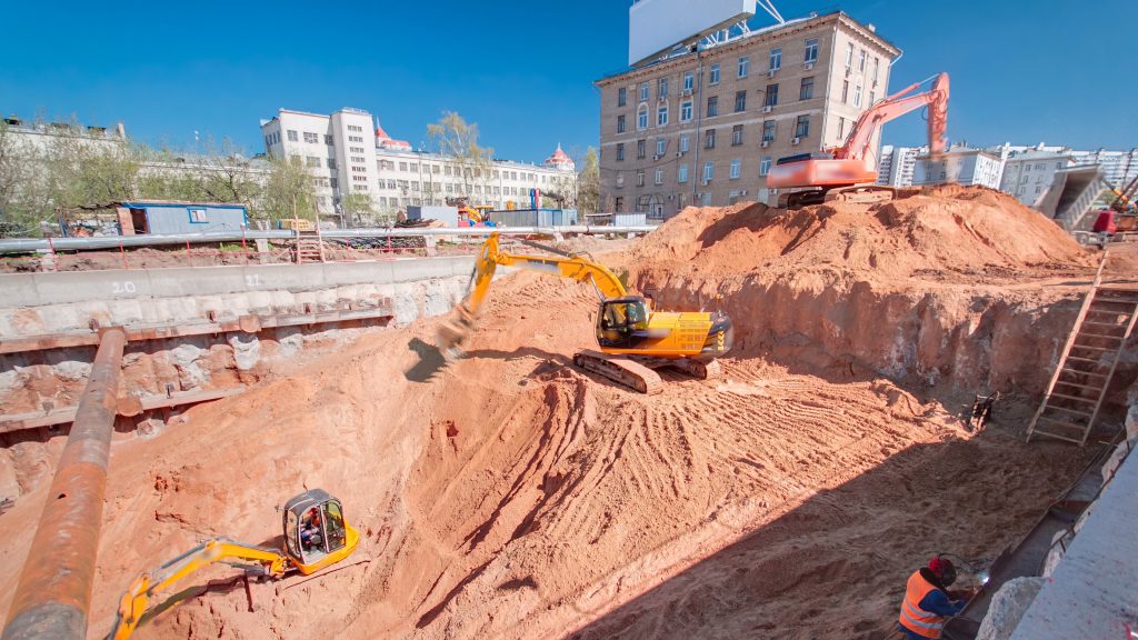An industrial excavator with its hydraulic arm fully extended is actively engaged in construction work
